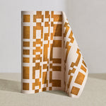 Wallpaper roll in a modernist checkerboard pattern in yellow ochre and cream.