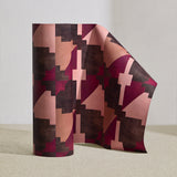 Wallpaper roll in a bold abstract checkerboard pattern in brown, tan, pink and fuchsia.