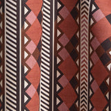 Wallpaper in a complex stripe with geometric shapes and chevrons in clay, lilac, brown and cream.