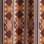 Wallpaper in a complex stripe with geometric shapes and chevrons in taupe, orange, oxblood and cream.