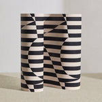 Wallpaper roll in a trompe l'oeil stripe pattern with geometric shapes in cream and black.