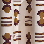 Wallpaper in a graphic geometric pattern of circles and stripes in maroon and ochre on a cream field. 
