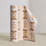 Wallpaper roll in a geometric stair step pattern in brown and tan on a cream field.