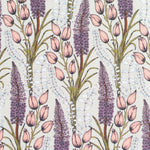 Detail of fabric in a dense foxtail and lilly print in pink, purple, green and white on a cream field.