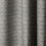 Draped linen fabric in a repeating abstract gridded pattern in navy on a cream field.