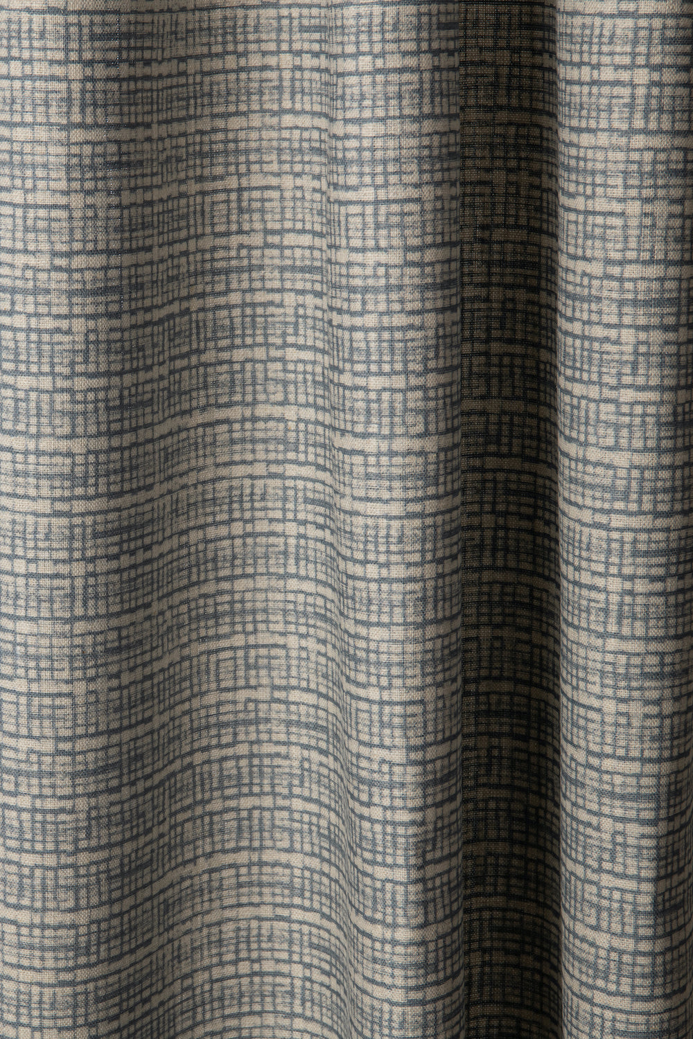 Draped linen fabric in a repeating abstract gridded pattern in navy on a cream field.