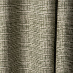 Draped linen fabric in a repeating abstract gridded pattern in sage on a cream field.