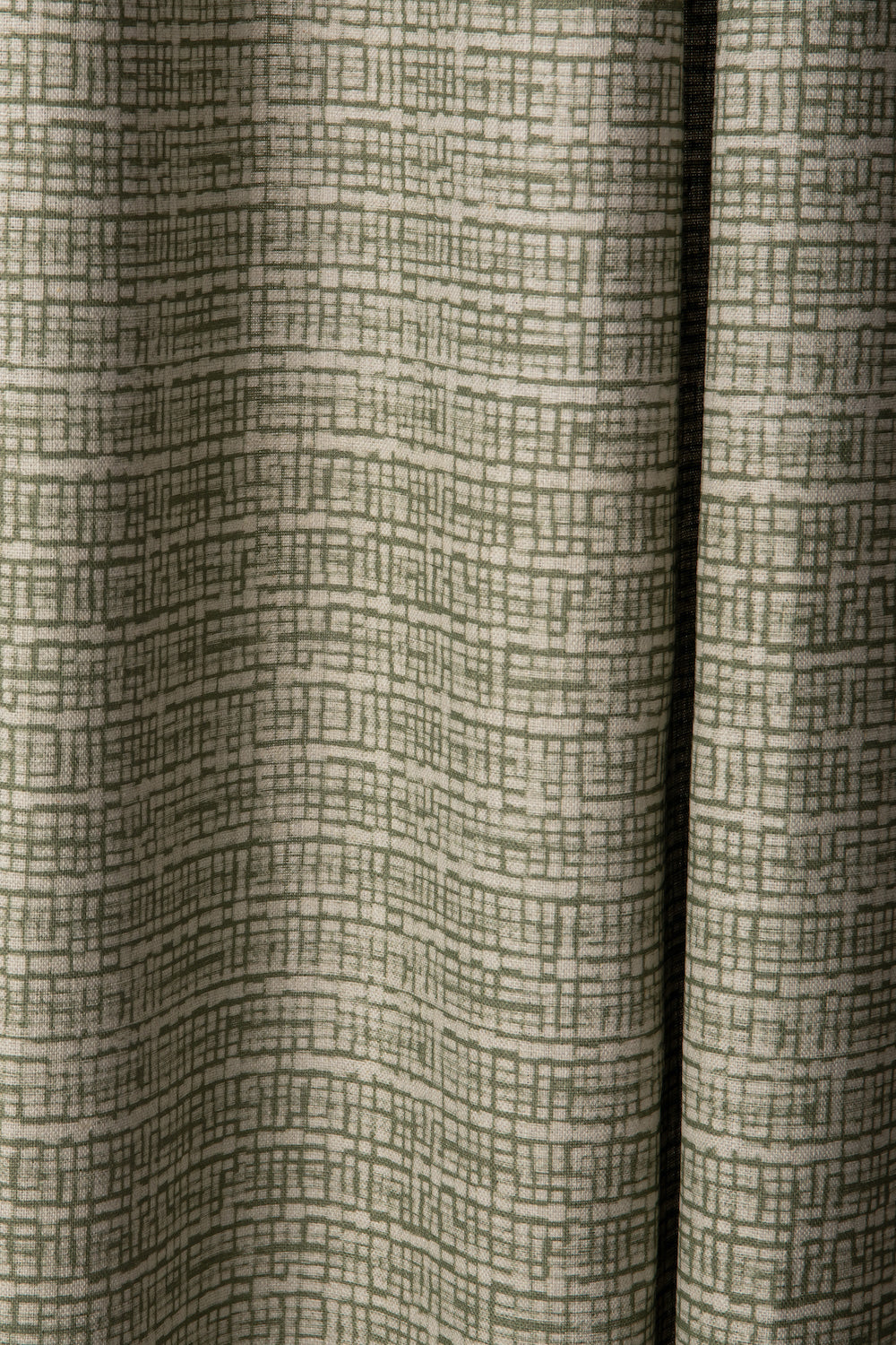 Draped linen fabric in a repeating abstract gridded pattern in sage on a cream field.