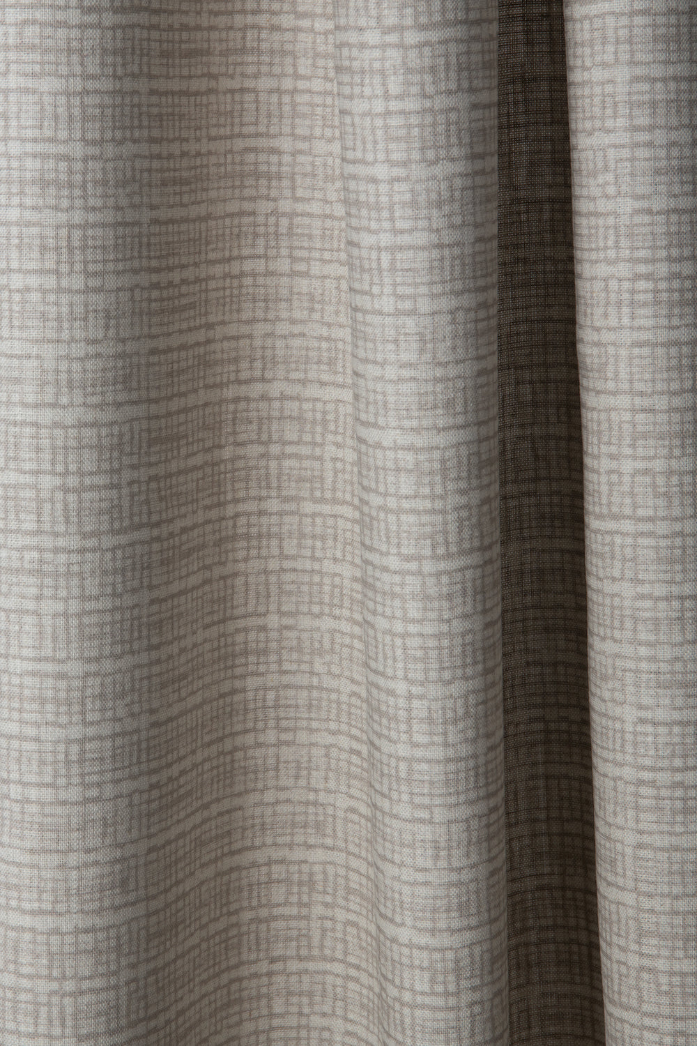 Draped linen fabric in a repeating abstract gridded pattern in beige on a cream field.