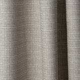 Draped linen fabric in a repeating abstract gridded pattern in beige on a cream field.