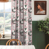 A cozy dining room with a large window and curtains in a minimalist floral grid print in white and green on a pink field.