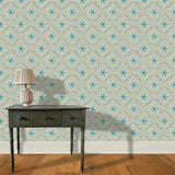 A wooden end table and lamp stand in front of a wall papered in an intricate floral lattice print in blue and tan.