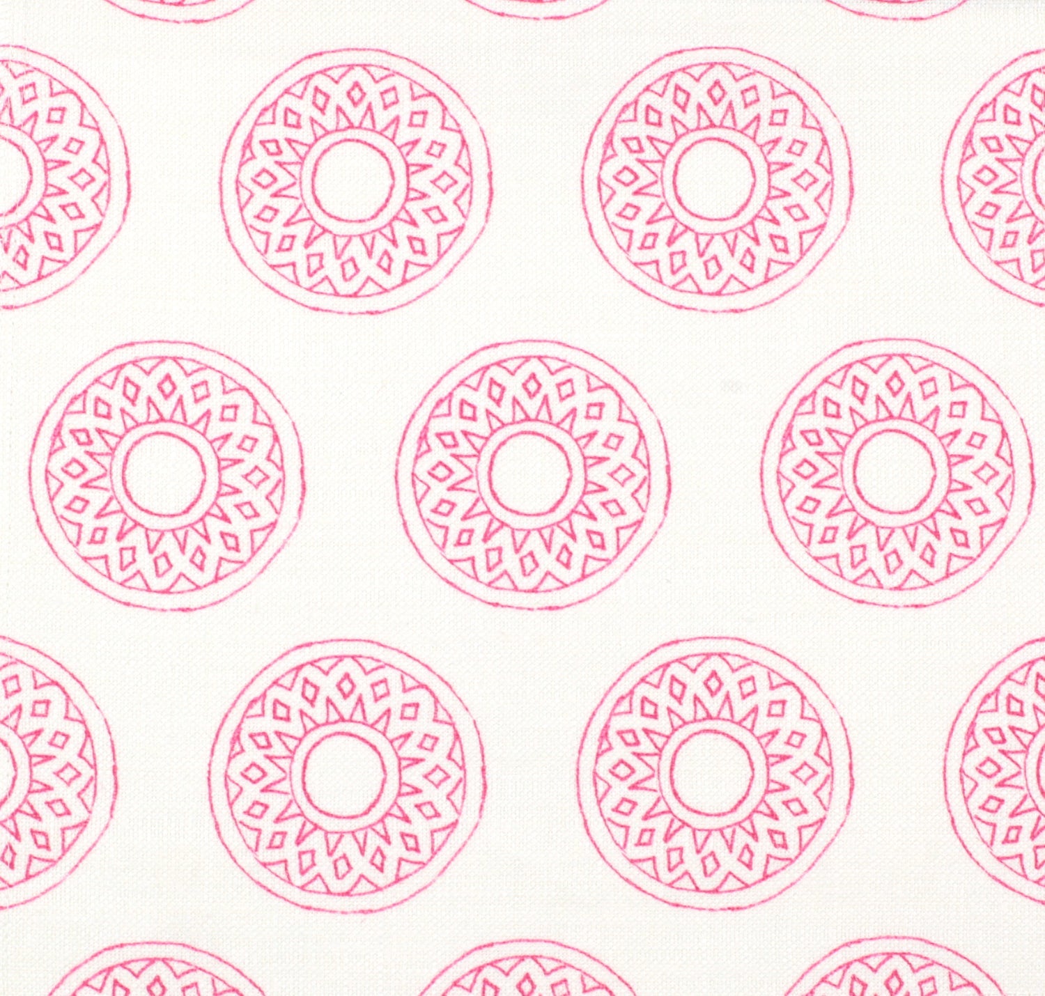 Detail of fabric in a repeating circular geometric print in pink on a white field.