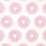 Detail of fabric in a repeating circular geometric print in pink on a white field.