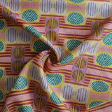 Close up of gently draped printed fabric with a complex geometric and striped pattern with pink, orange, turquoise and red. 