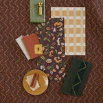 Moodboard with layered swatches of fabrics and inspiration images in palette of  brown, green and tan. 