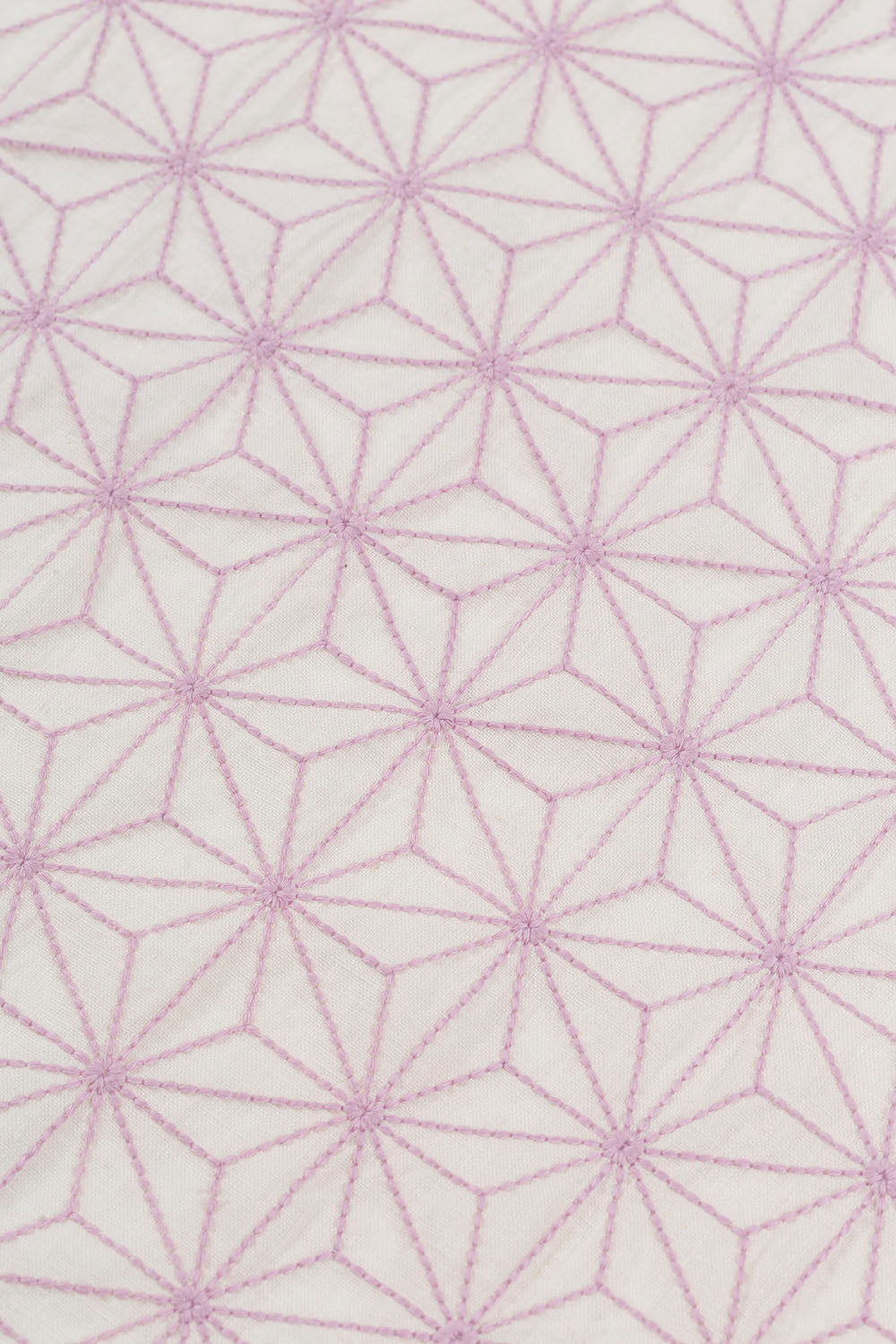 Fabric yardage with an embroidered floral lattice print in light purple on a cream field.