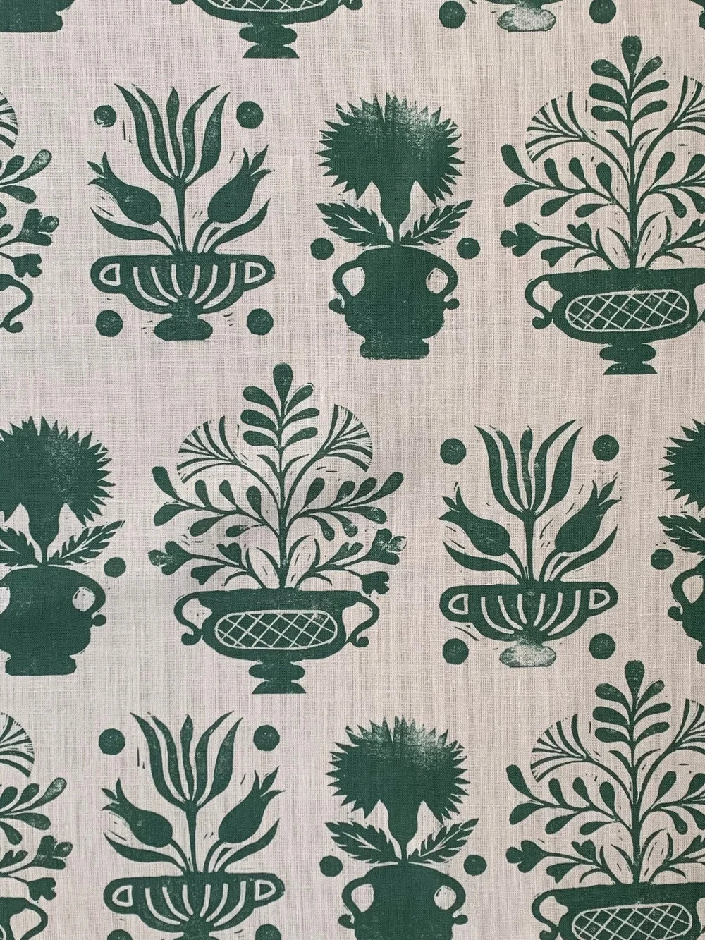 Patterned fabric with green floral and urn designs on a beige background