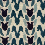 A close-up of a handknotted rug with an abstract petal design in wine purple, teal and aqua blue on a cream field. 