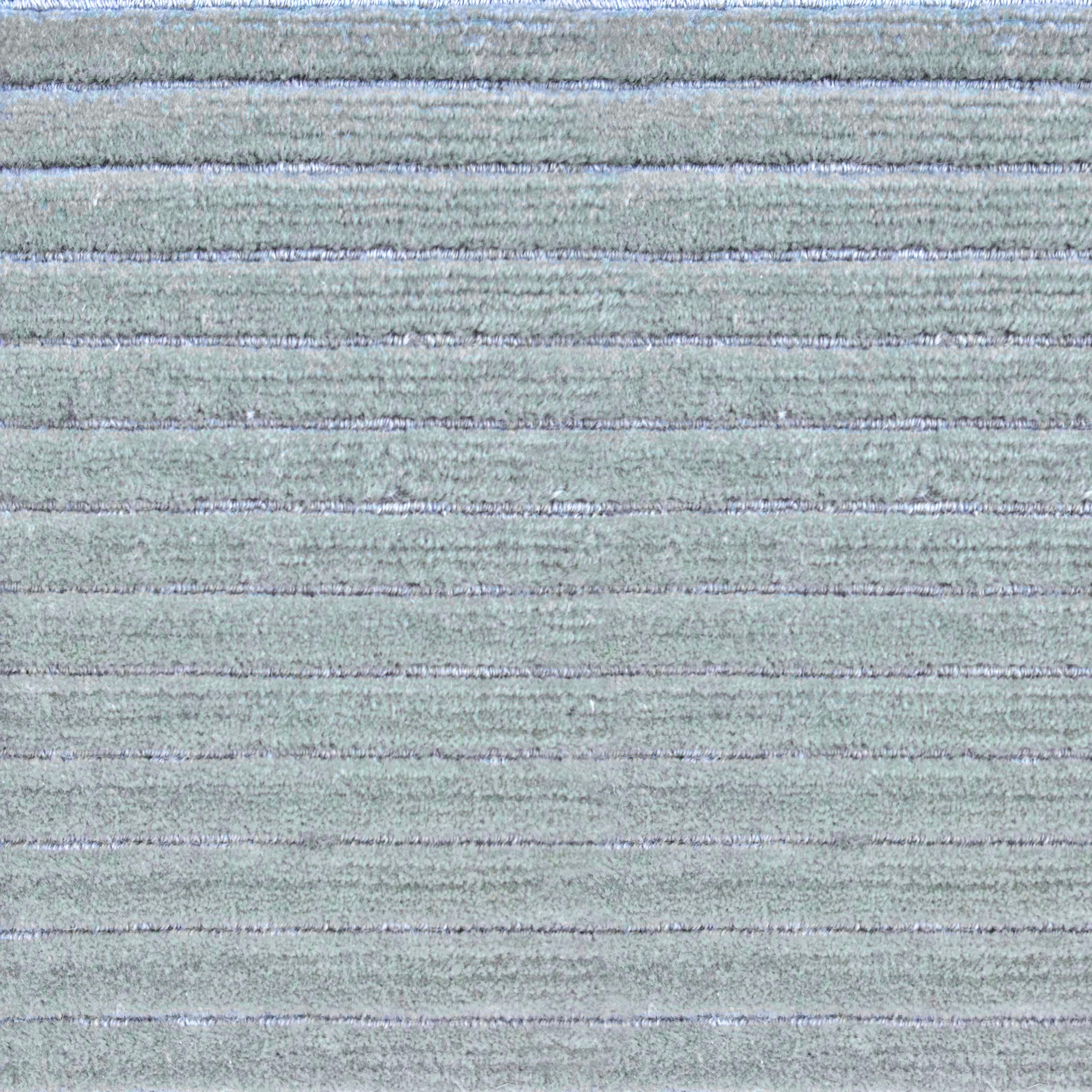 Detail of a handknotted rug in a raised stripe pattern in light grey