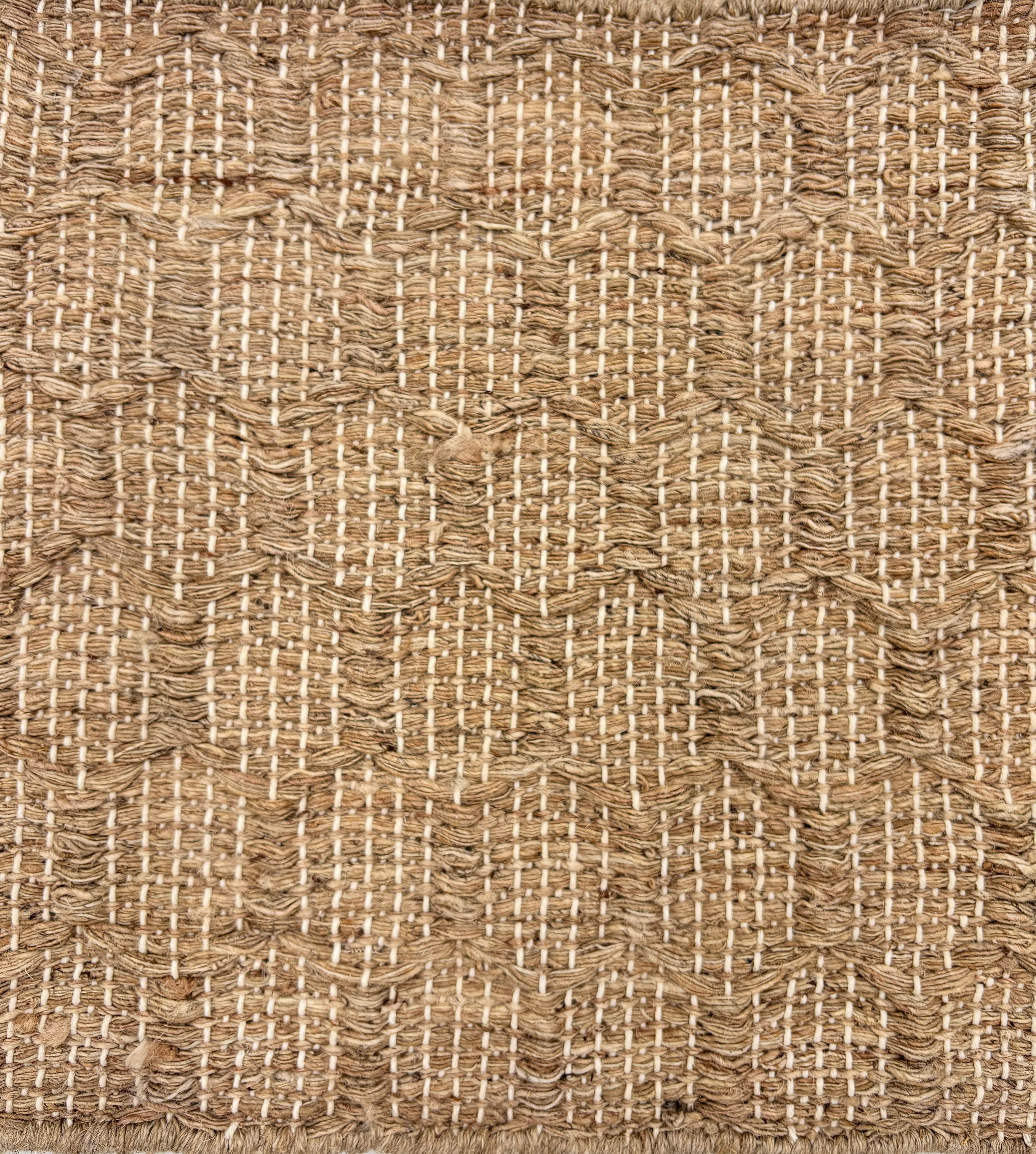Detail of a handwoven rug in a raised geometric lattice in natural jute fibers.