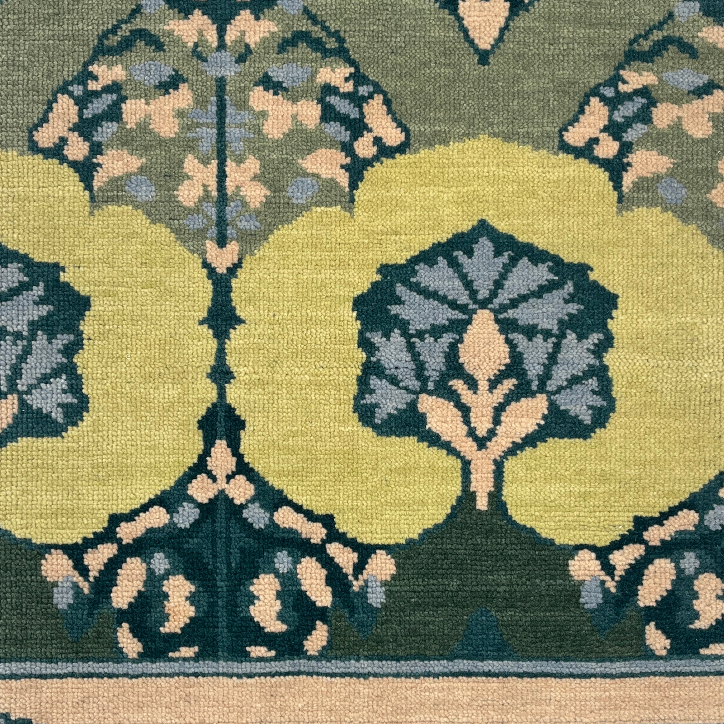 Close-up of a patterned rug with green, beige, and blue colors.