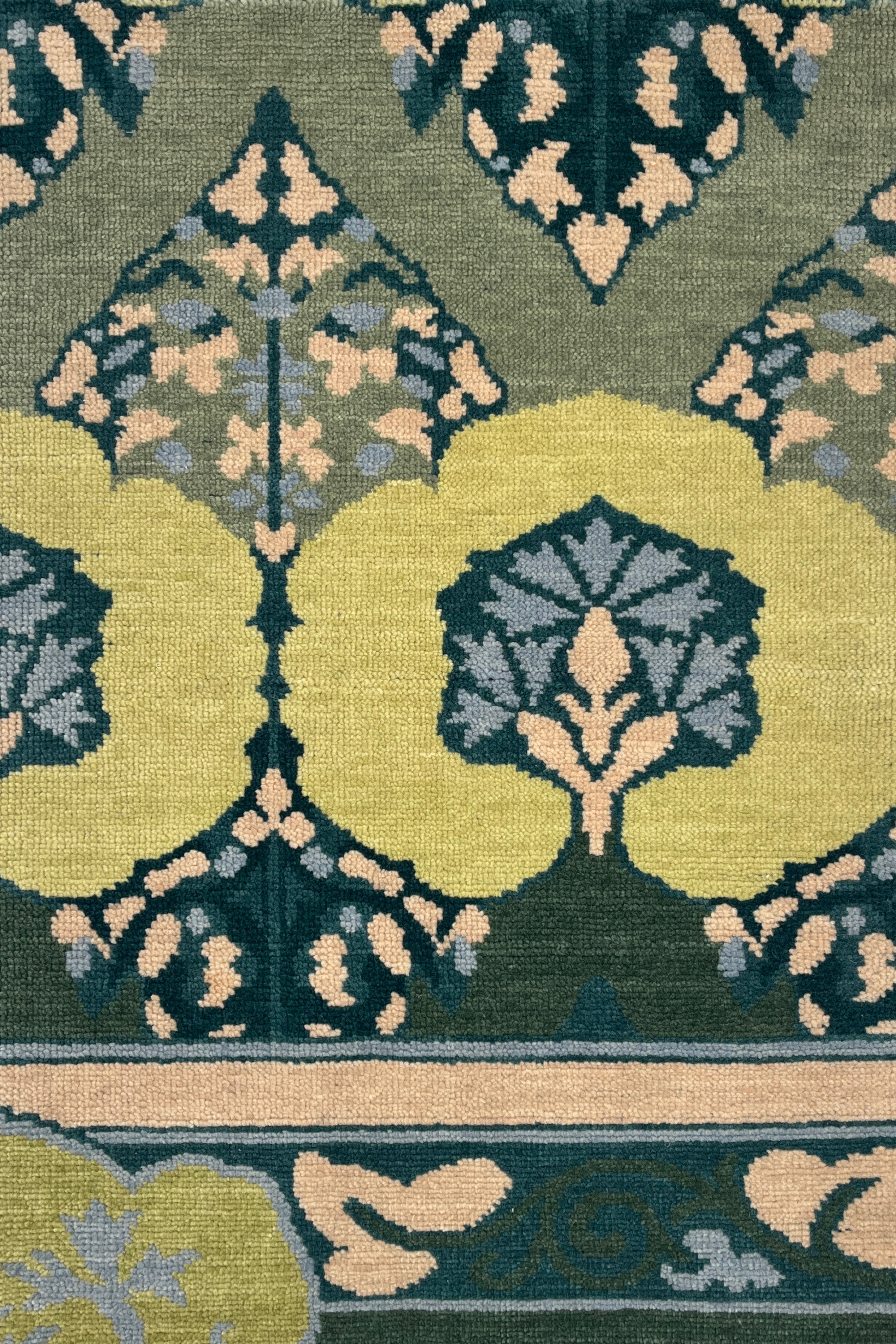 Close-up of a patterned rug with green, beige, and blue colors.