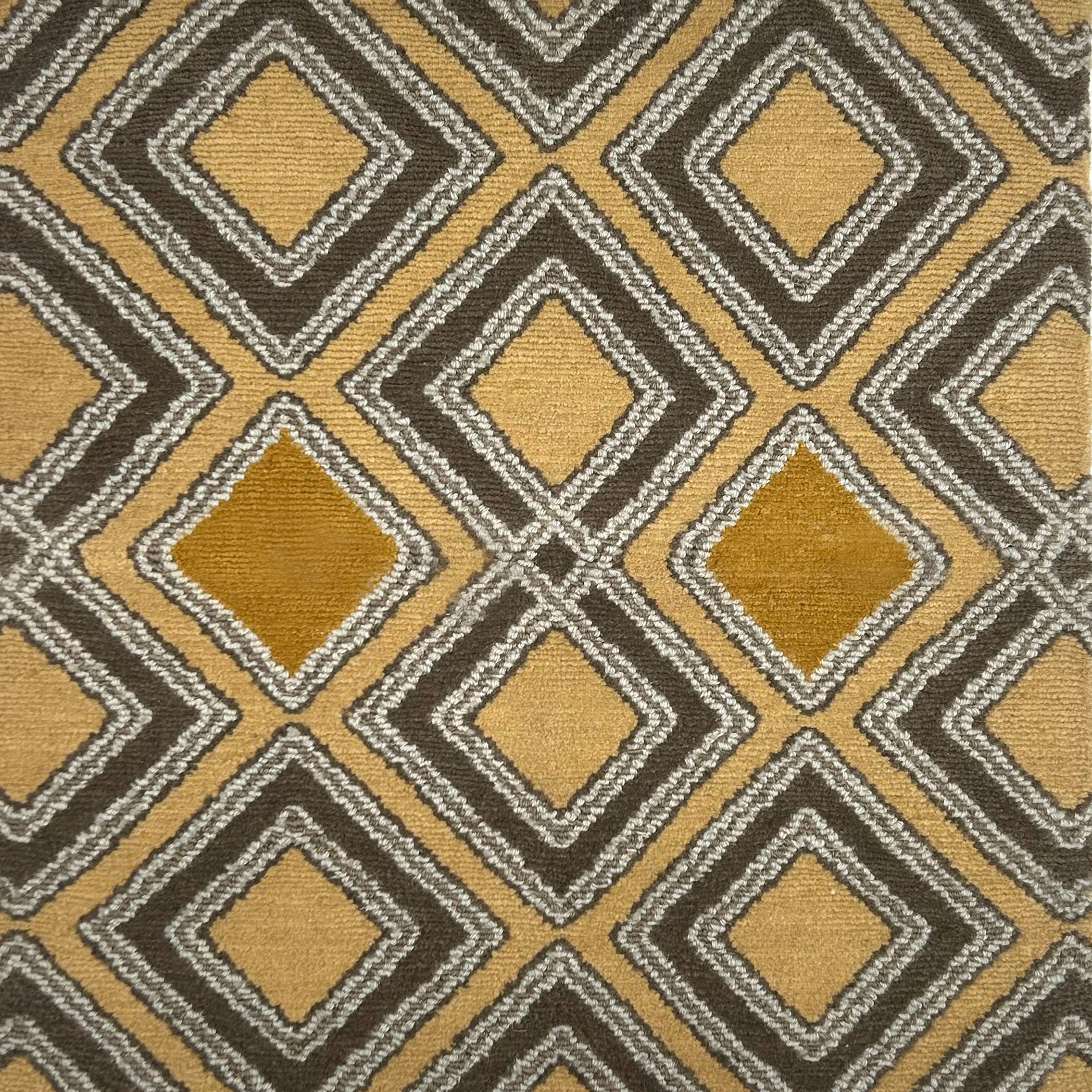 Handknotted rug in a diamond pattern in grey, cream and yellow on a tan field. 