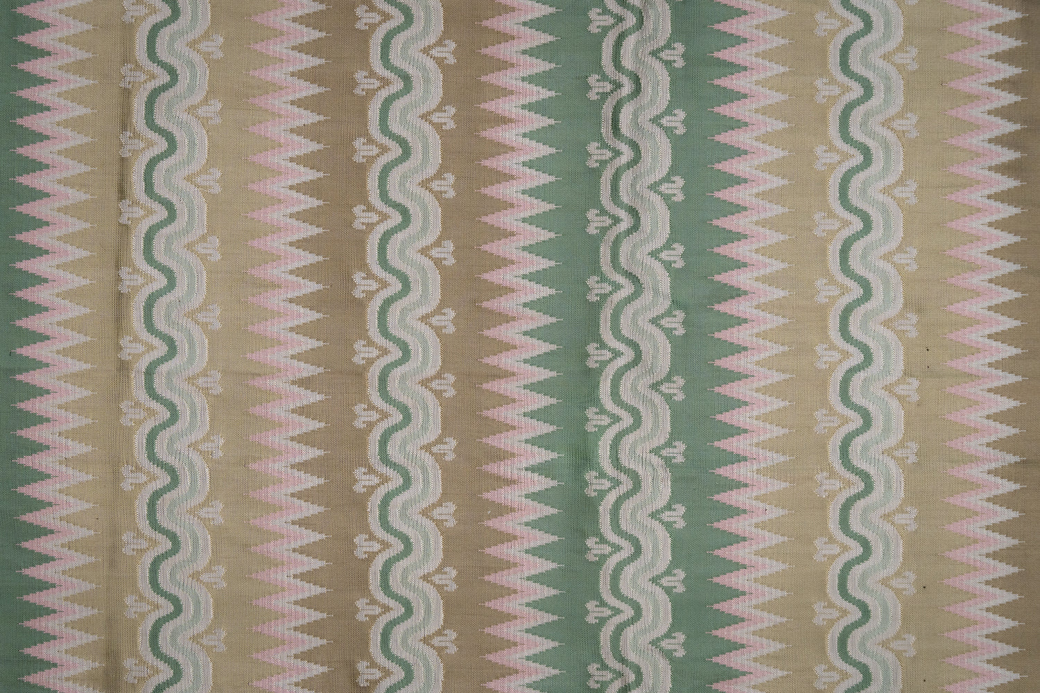 Handwoven silk fabric with wavy lines in beige green, and pink.