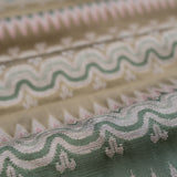 Close-up of patterned fabric with wavy lines and geometric shapes in green, tan and pink