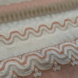 Close-up of patterned fabric with wavy lines and geometric shapes in pink, cream and beige. 