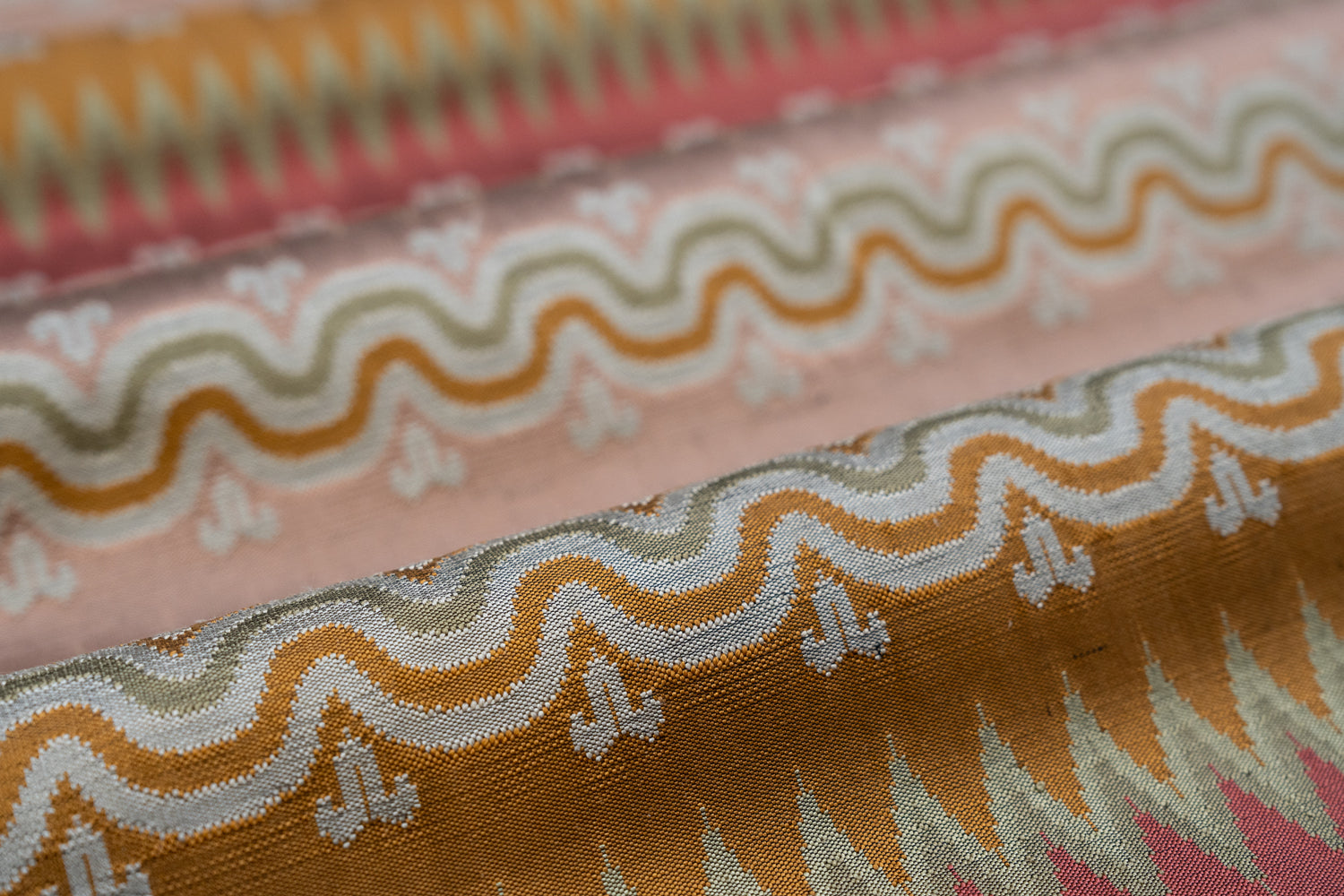 Close-up of patterned fabric with wavy lines and geometric shapes in pink, orange and red. 