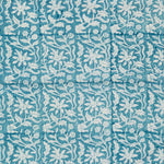 Detail of fabric in a floral block print in white on a turquoise field.