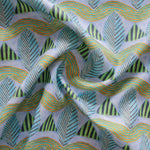 A close-up of a gently draped patterned fabric featuring repeating rows of stylized green leaves and wavy olive-yellow lines, striped blue and green triangles on a pale purple background.