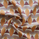 A close-up of a gently draped patterned fabric featuring repeating rows of stylized orange leaves, navy and red striped triangles and wavy orange-blue lines on a white background