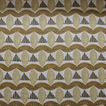 A close-up of a patterned fabric featuring repeating rows of stylized tan leaves, brown and green striped triangles and wavy tan-green lines on a white background
