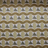A close-up of a patterned fabric featuring repeating rows of stylized tan leaves, brown and green striped triangles and wavy tan-green lines on a white background