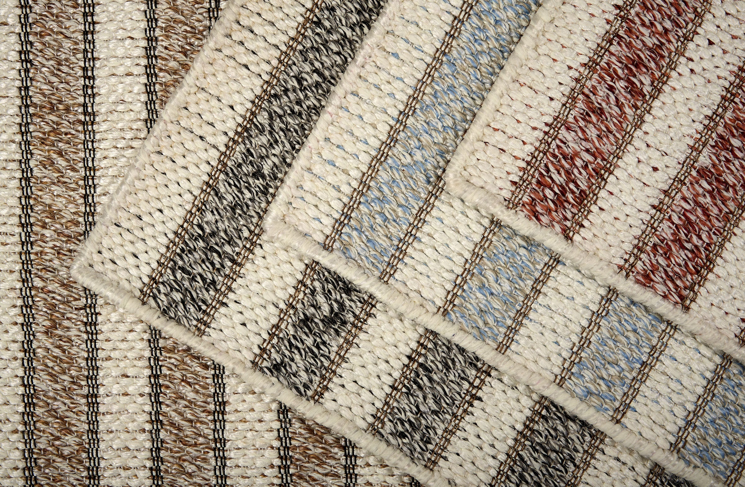 Close-up of textured area rugs with striped pattern in various colors. 