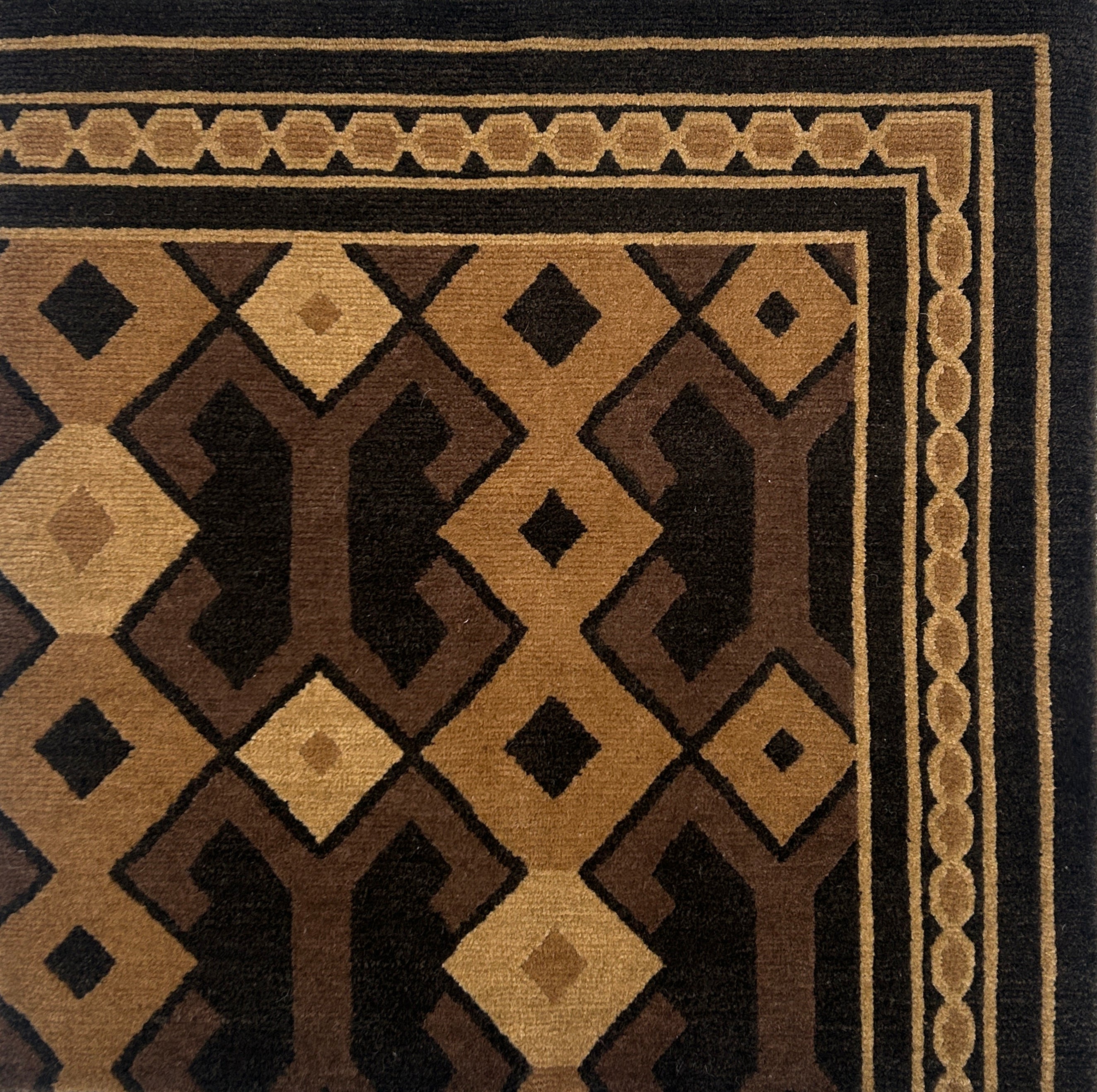 Close-up of a patterned rug with geometric design in brown and black.