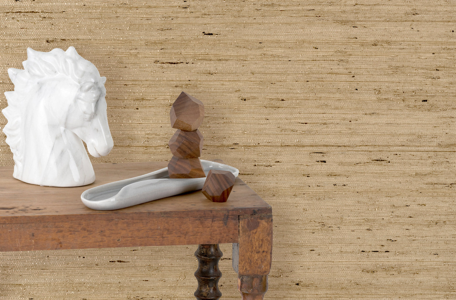 End table with marble and wood scupltures in front of a wall papered in textured tan arrowroot grasscloth.
