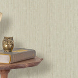 End table with books and  vintage phone in front of a grasscloth wallpaper with a herringbone weave in cream and beige.