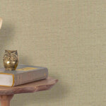 End table with a phone, book and owl sculpture in front of a wall covered in paperweave grasscloth in natural taupe.