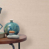 End table with a vase, horse sculpture and stones in front of a wall covered in sisal grasscloth in pale pink.