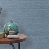 End table with a vase, horse sculpture and stones in front of a wall covered in sisal grasscloth in mottled blue.