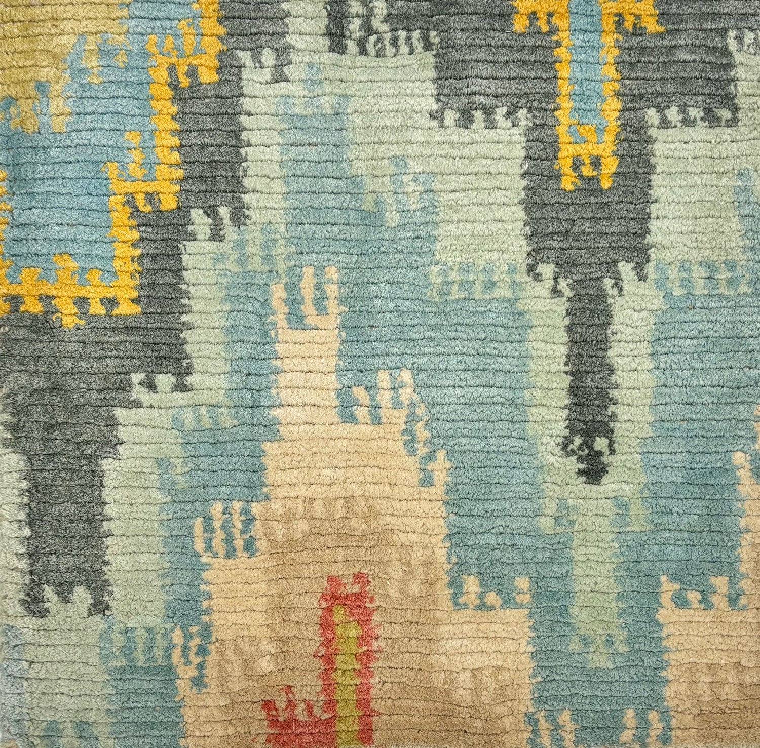 Handknotted rug sample in a ikat flamestitch pattern in blue, grey, ivory, yellow and coral. 
