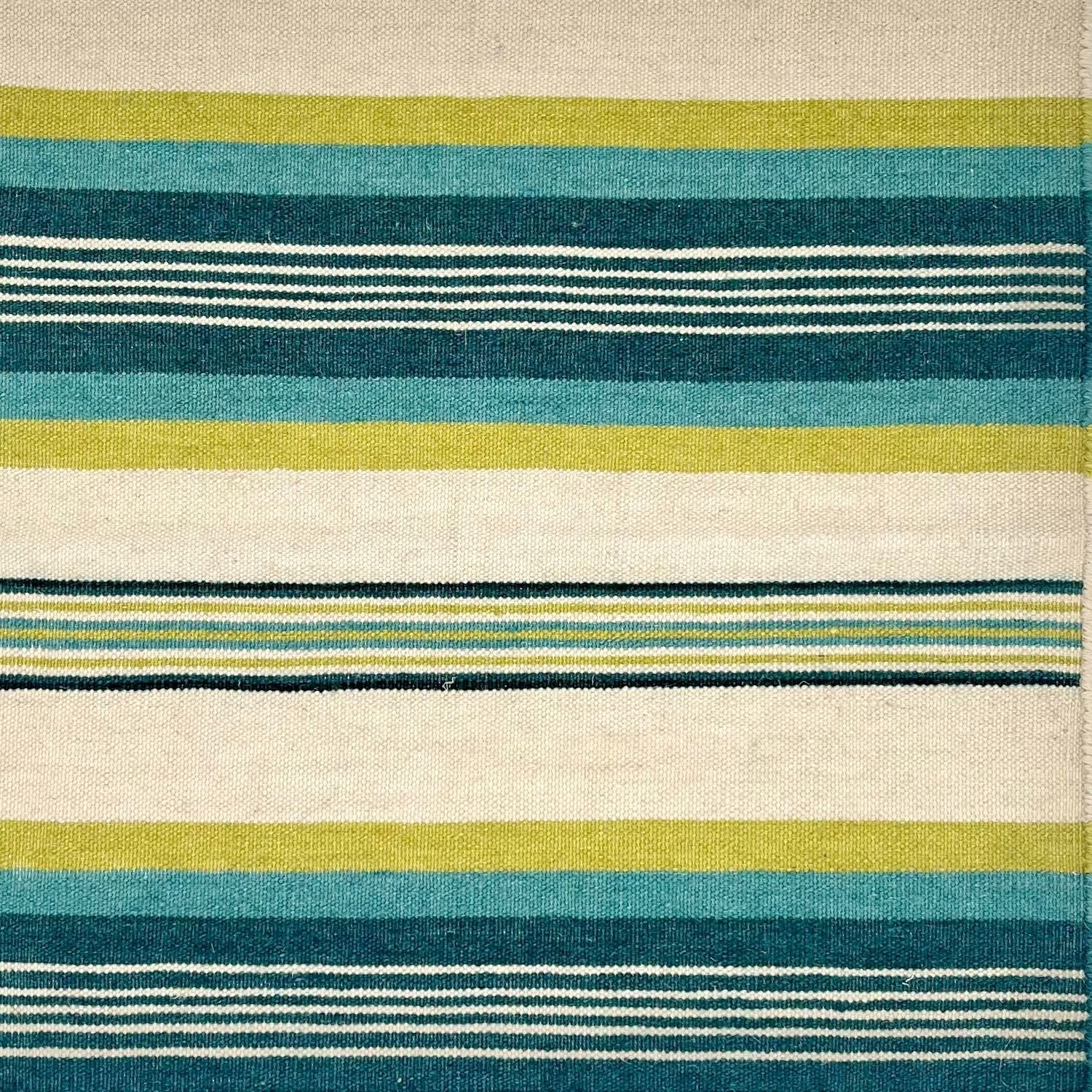 A flatweave rug with mix width stripes in lime green, turquoise, deep teal and ivory.