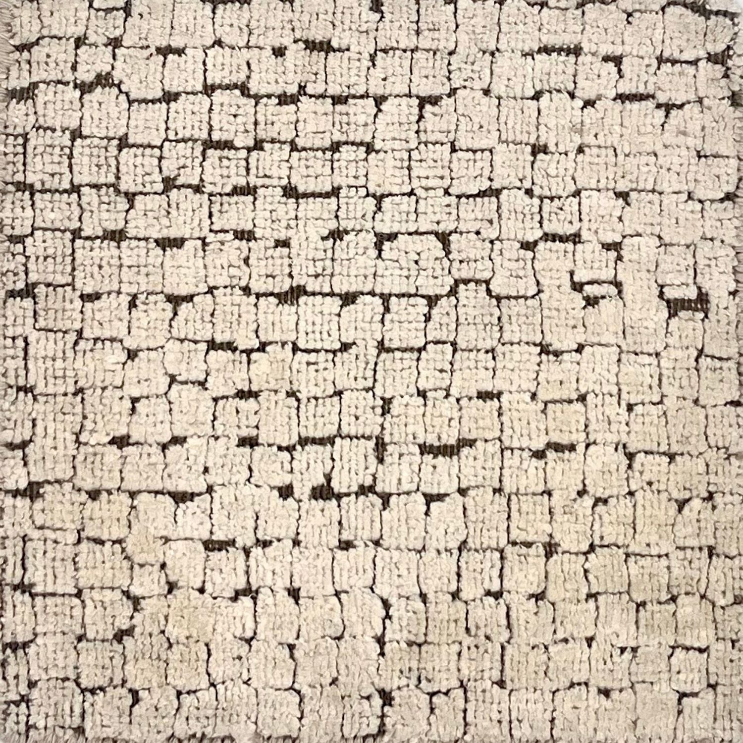 A rug with irregular squares generally in stripes with a brown ground and ivory squares.