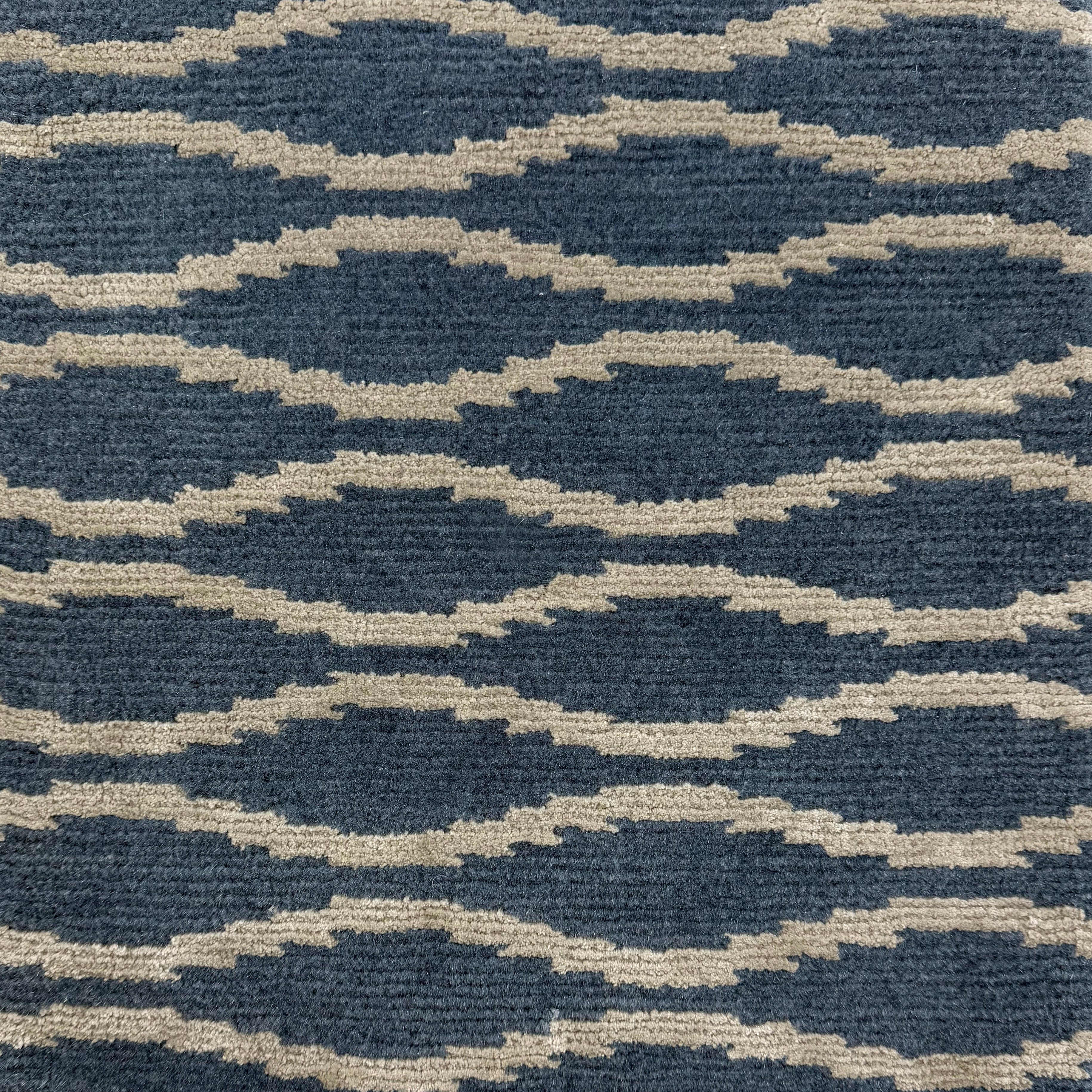 Handknotted rug with serpetine stripe in grey on a blue field. 