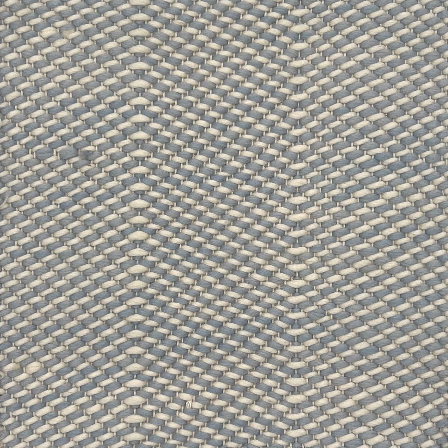 Flatweave rug with grey and white twisted yarns in a herringbone pattern. 