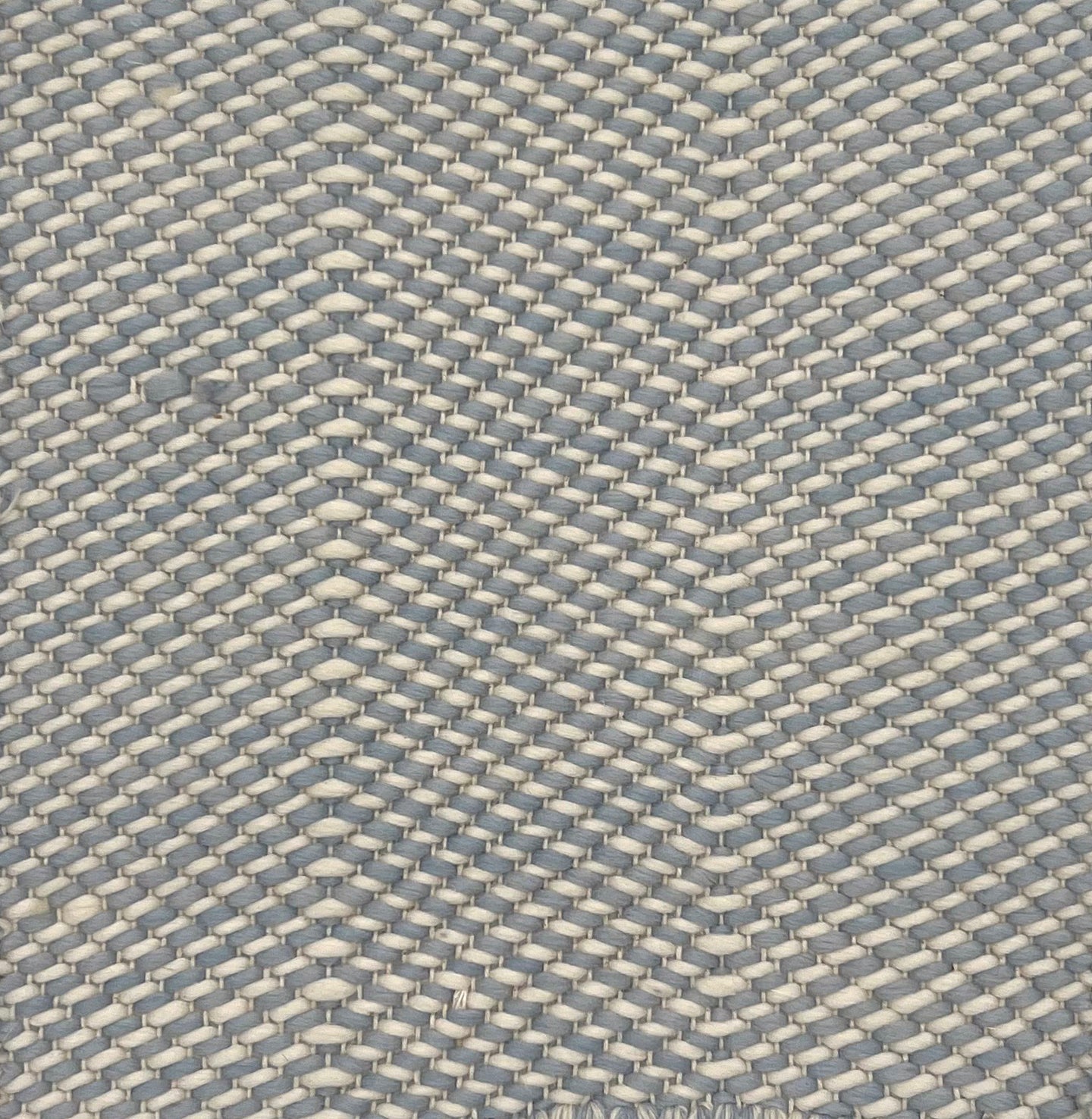 Flatweave rug with grey and white twisted yarns in a herringbone pattern. 